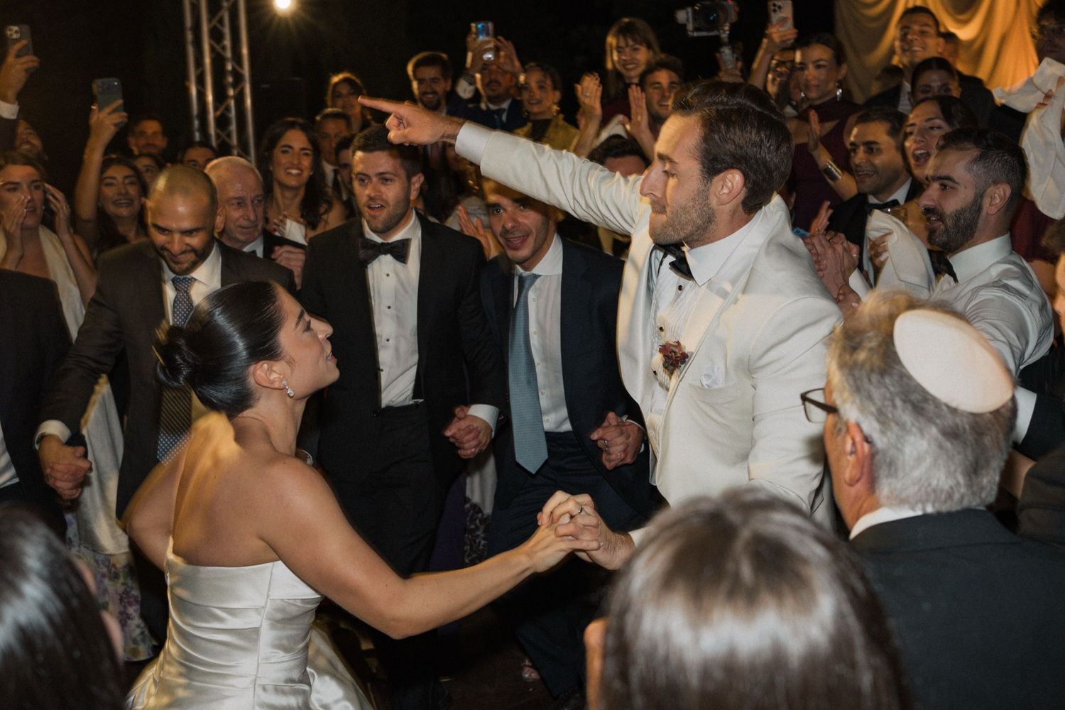 Wedding guests dance and celebrate on a crowded dance floor at an elegant evening reception.