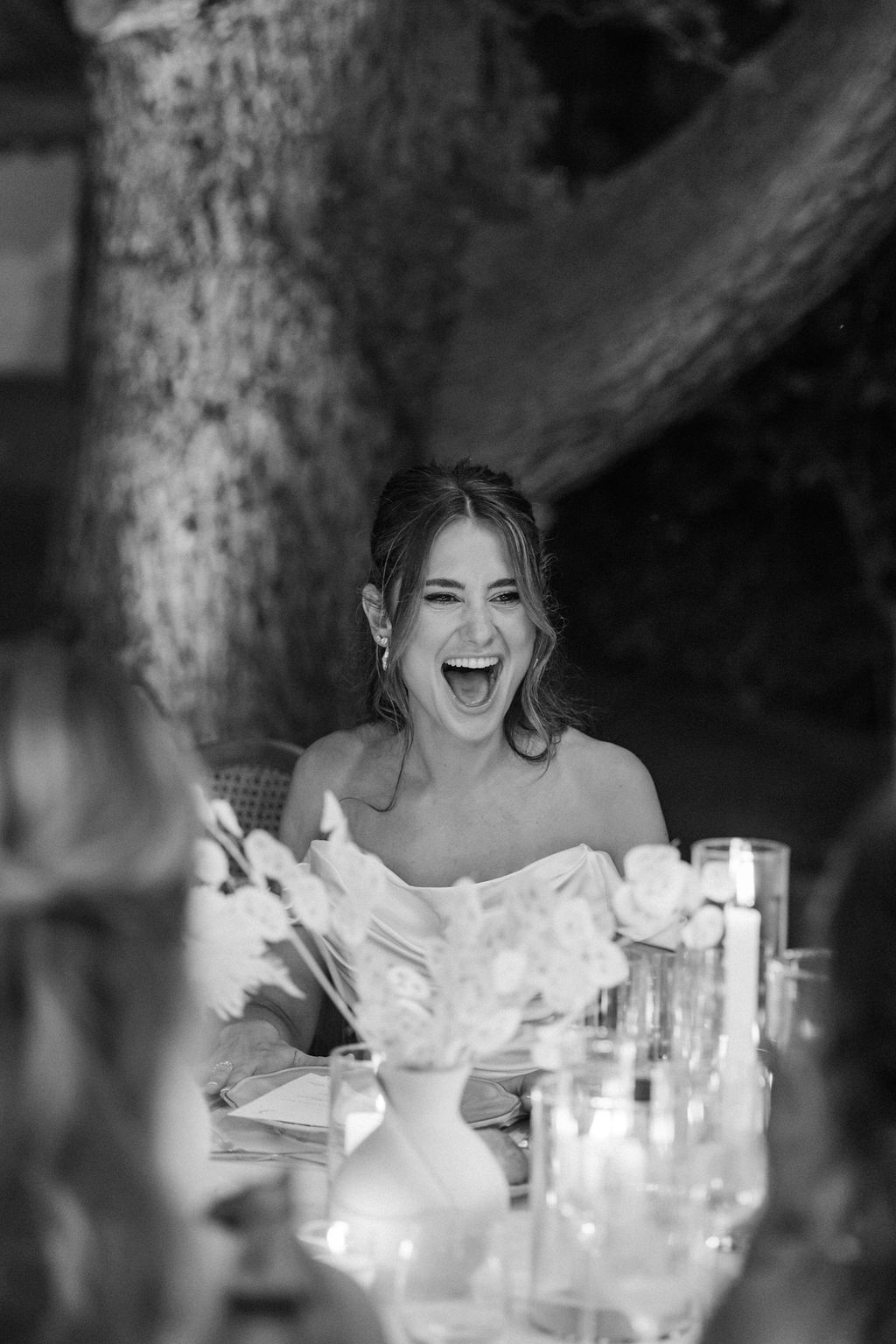 Joyful reactions captured during wedding reception speeches at a candlelit table.