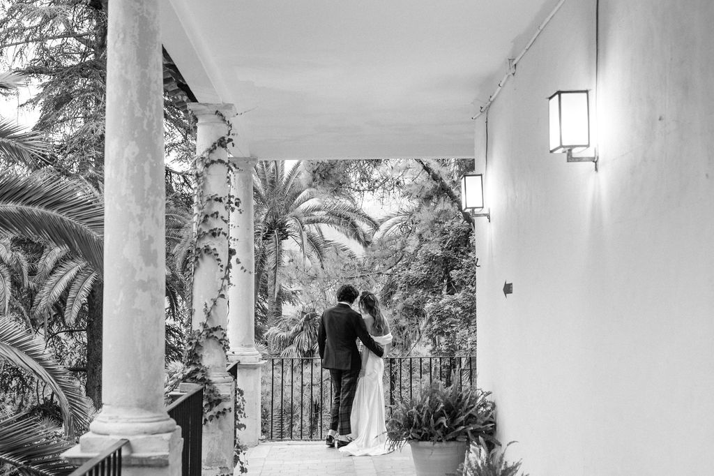 Black and white photo of couple walking down elegant columned porch.