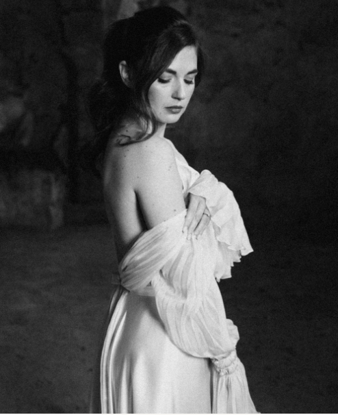 Artistic black and white bridal portraits showing a flowing white dress against a dark background.