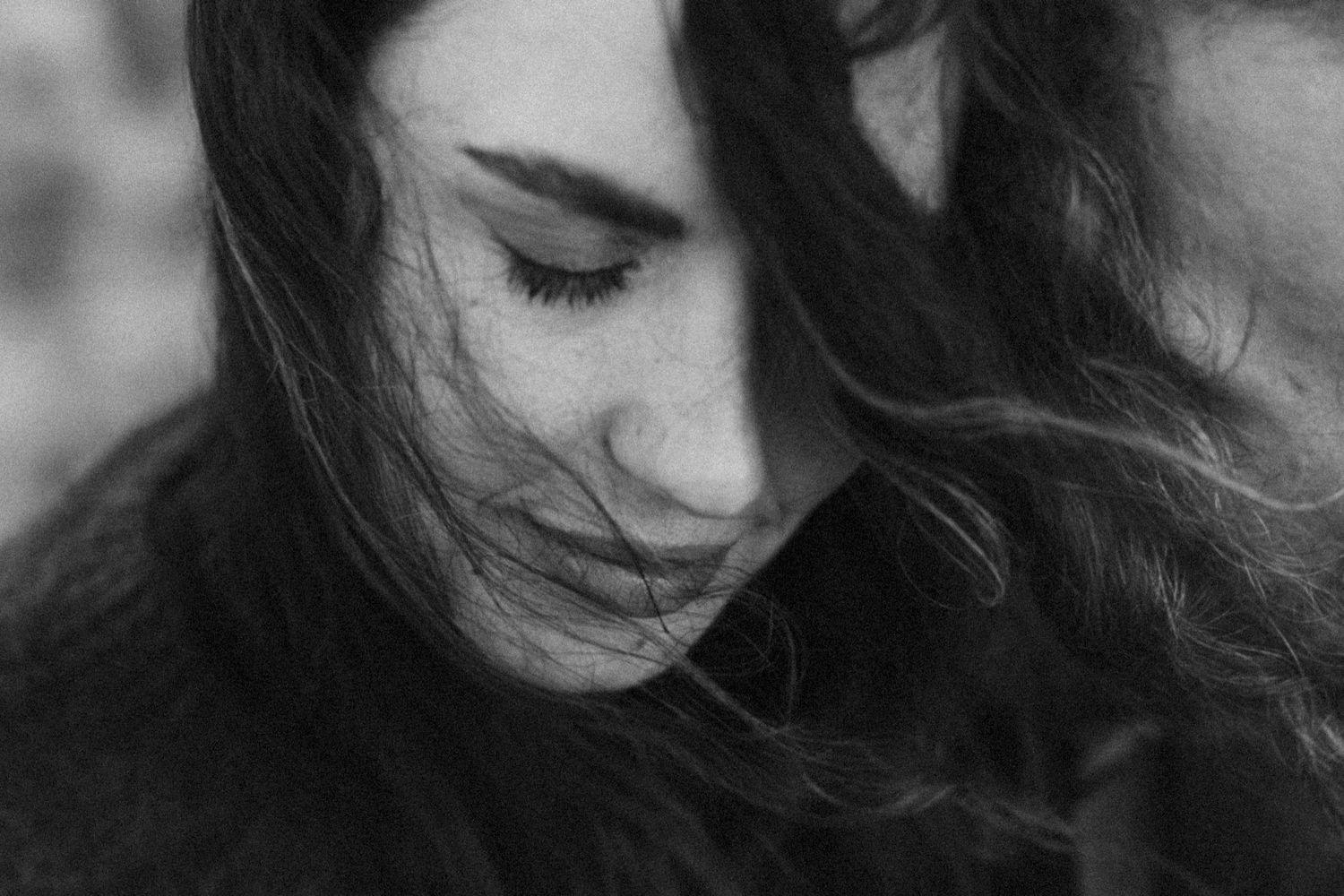 A series of black and white portraits showing a person with flowing dark hair in different poses and expressions.