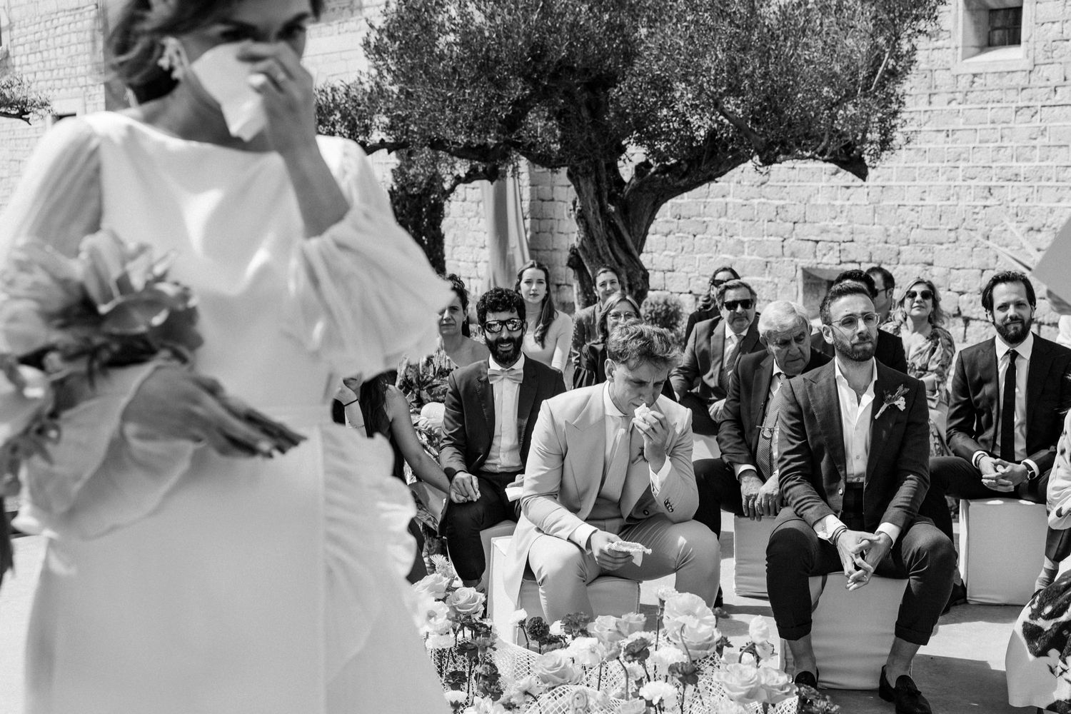 Wedding guests celebrate and dance during an outdoor reception at a rustic venue.