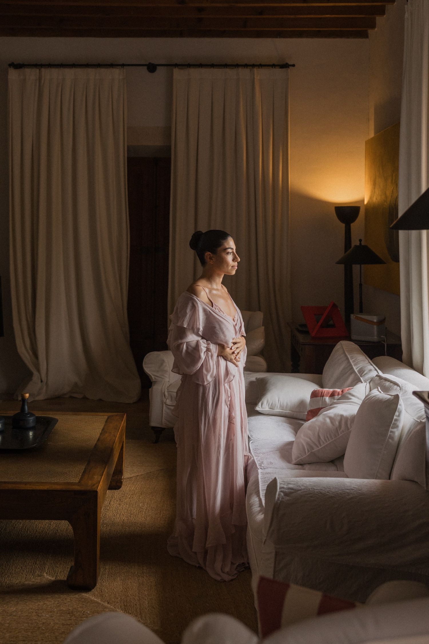 A series of moody boudoir photos showing a figure in a pink robe moving gracefully in a dimly lit bedroom.