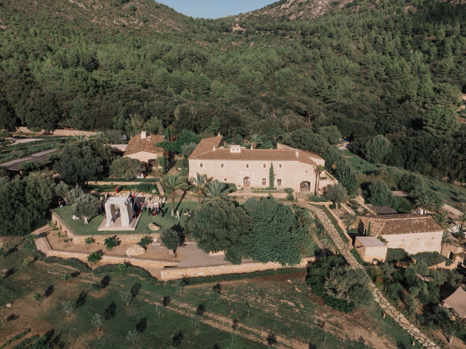 Aerial view of a luxurious estate nestled in the hills with multiple buildings and manicured grounds.