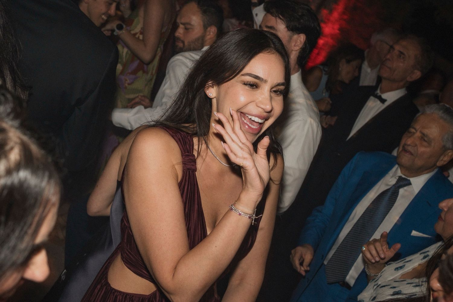 A person laughs and covers their mouth while sitting in a dark audience setting during an event.