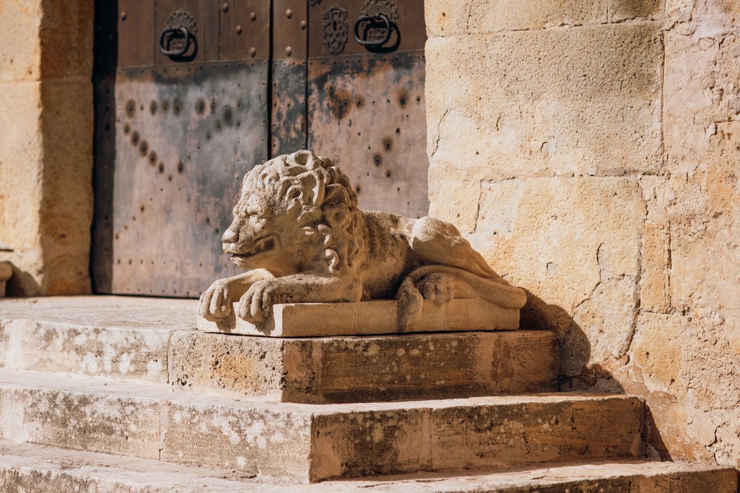 Ancient stone architectural details with ornate carvings and lion sculptures along a historic building facade.