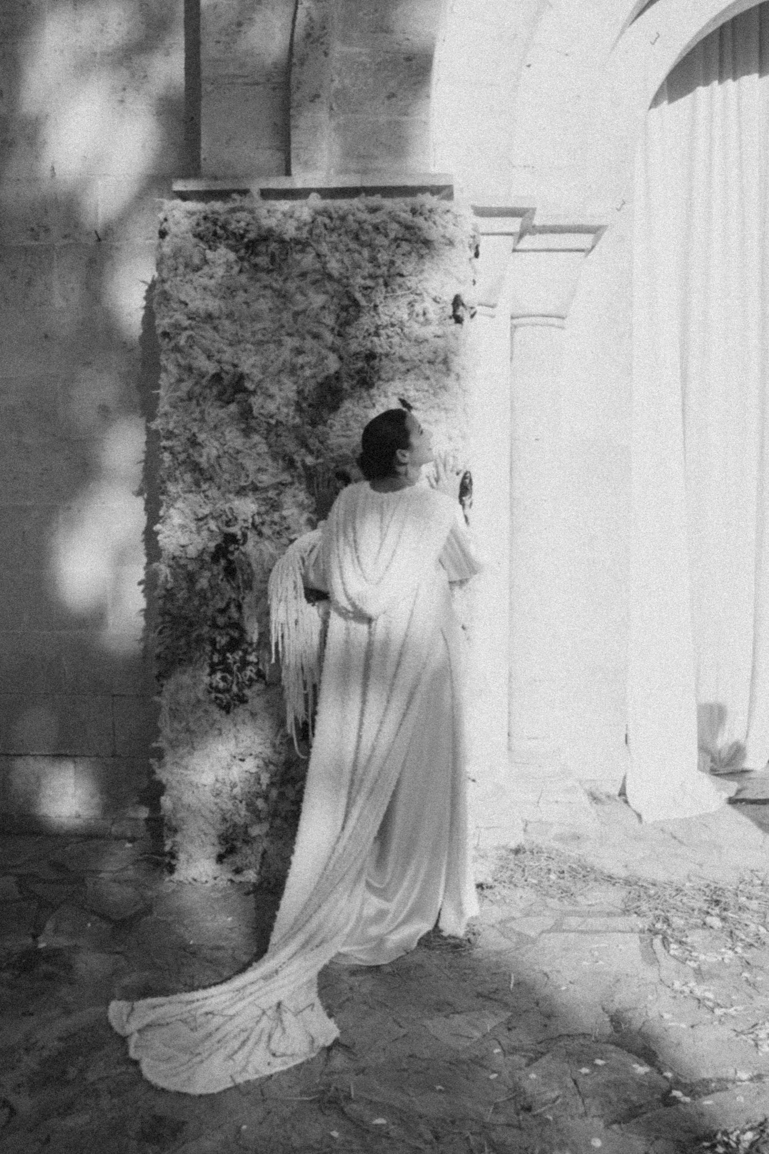 Sequential black and white images showing a figure in white dress moving gracefully near stone walls.