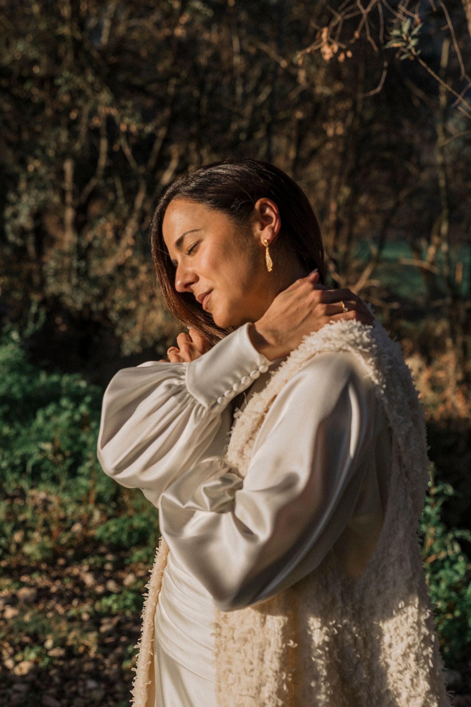 Ethereal sunlit portrait featuring a vintage-style white lace dress in a forest setting.