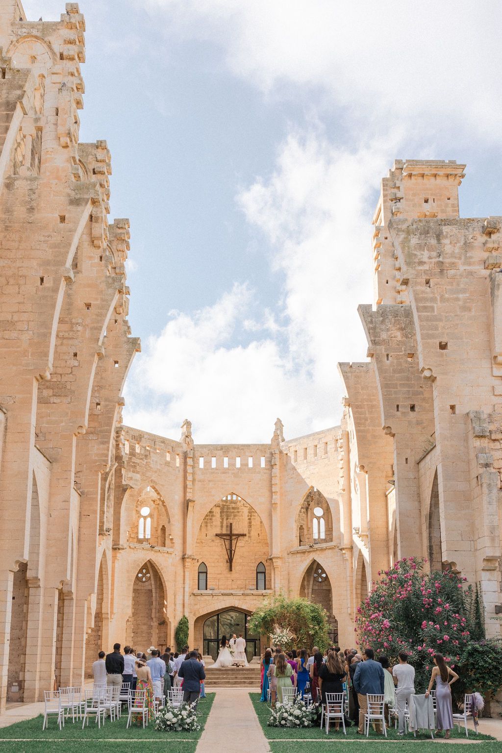 Elegant stone cathedral with towering Gothic arches and white chairs set up for an outdoor ceremony.