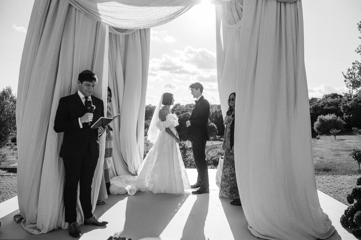 A series of black and white wedding photos showing silhouettes and moments from a romantic outdoor ceremony.