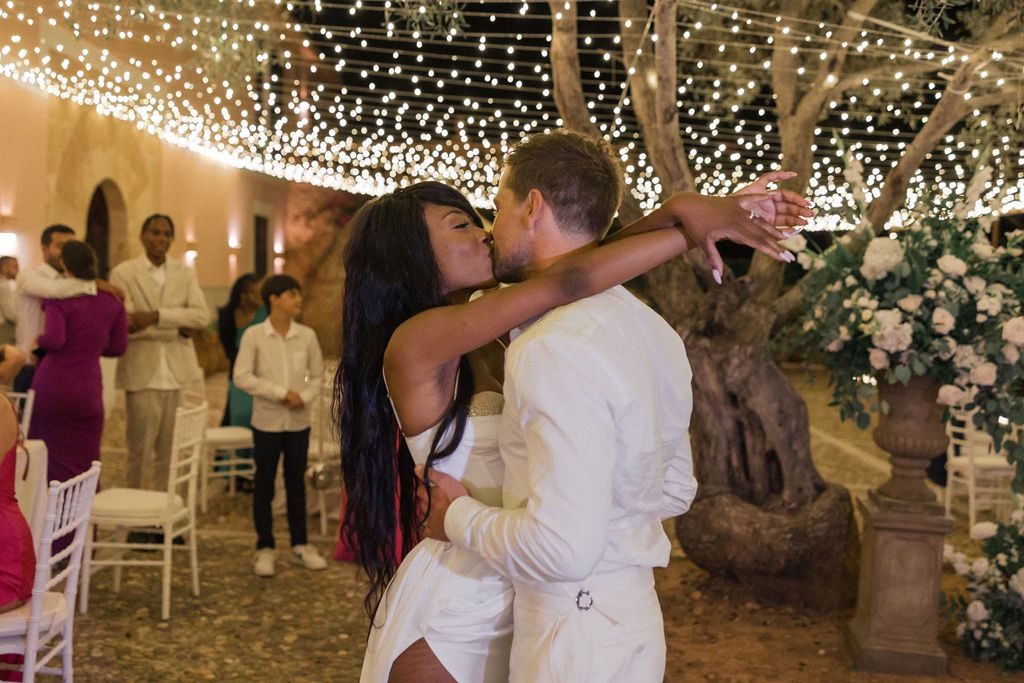 A couple dances intimately beneath a canopy of sparkling lights during their wedding celebration.
