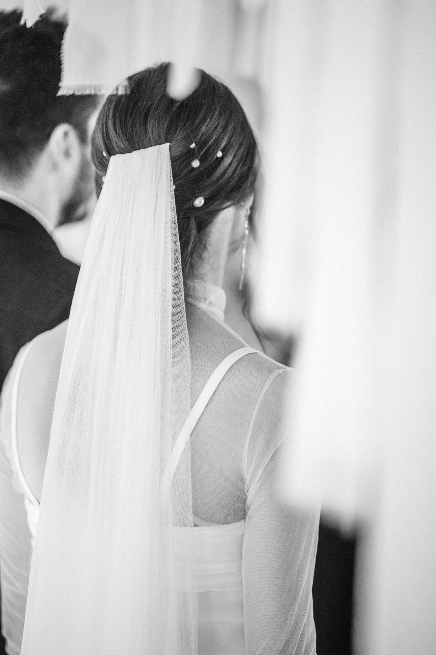 A series of black and white photos showing the back of a bride's veil and wedding dress from different angles.