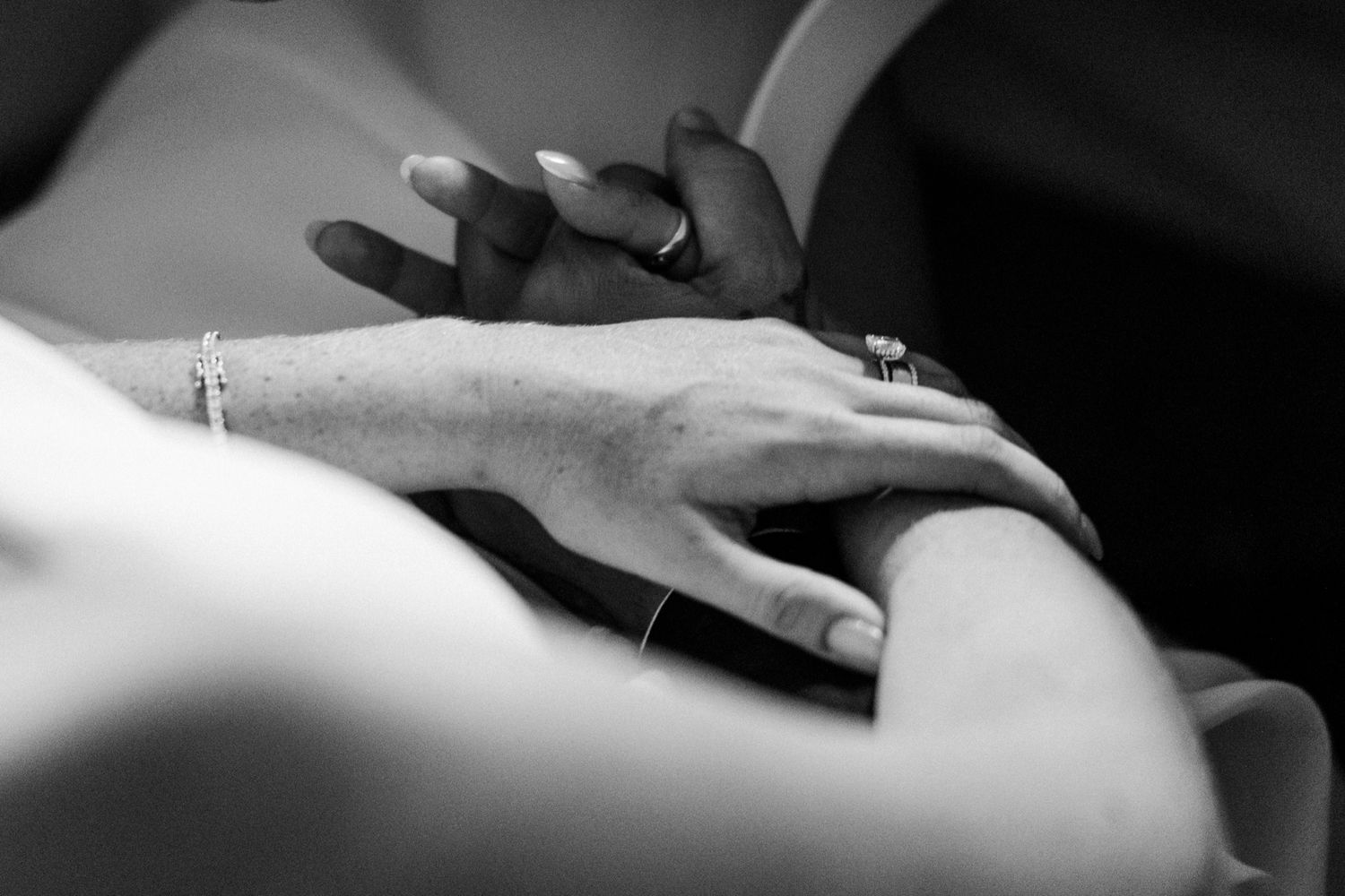 Close-up details of hands and jewelry in black and white.