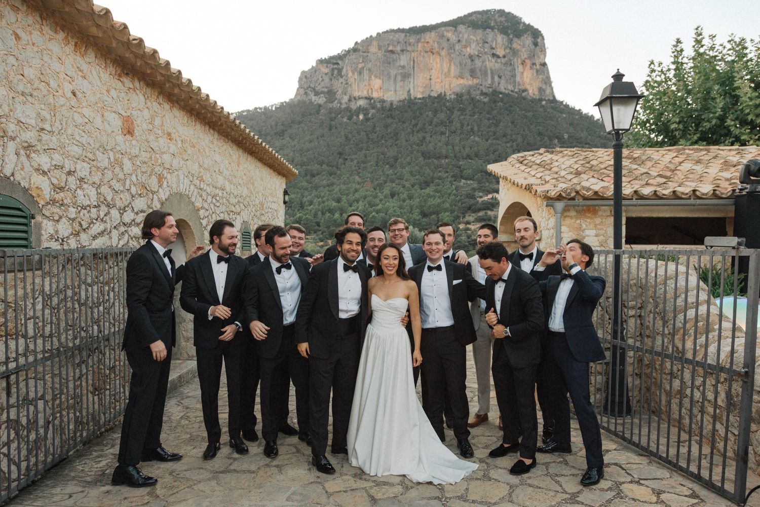 Wedding party stands together on a rustic stone terrace with mountain views in the background.