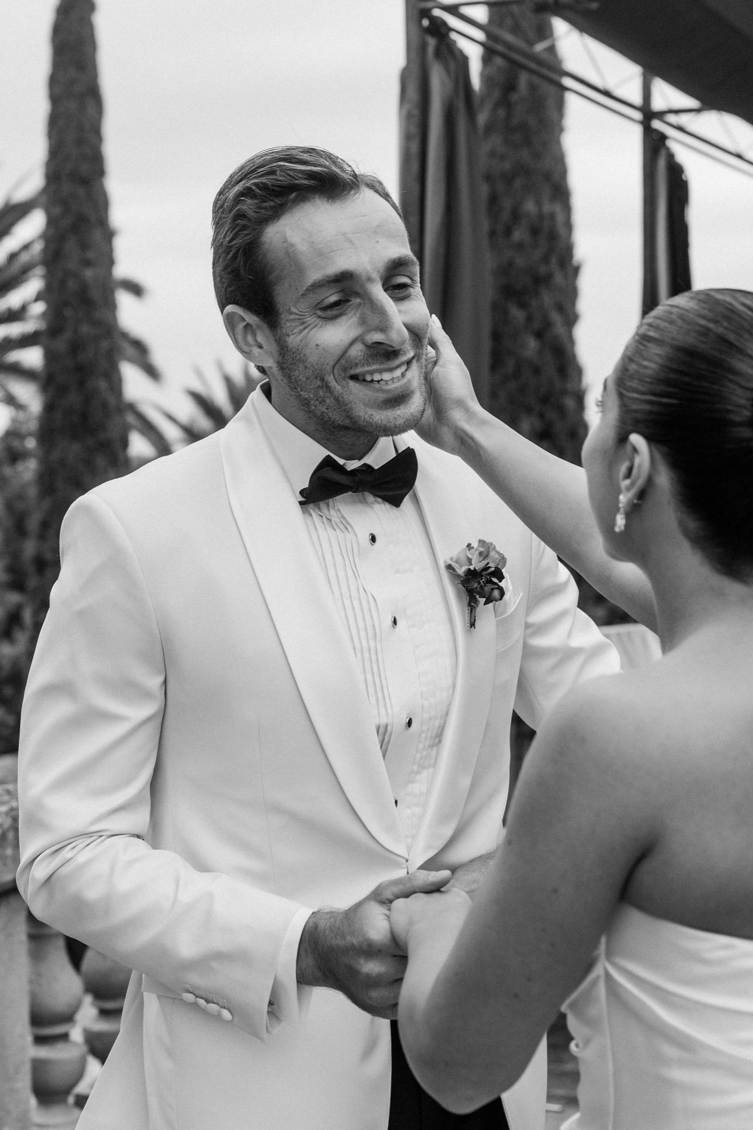 A tender moment between newlyweds at an outdoor wedding ceremony as they share a joyful exchange in formal attire.