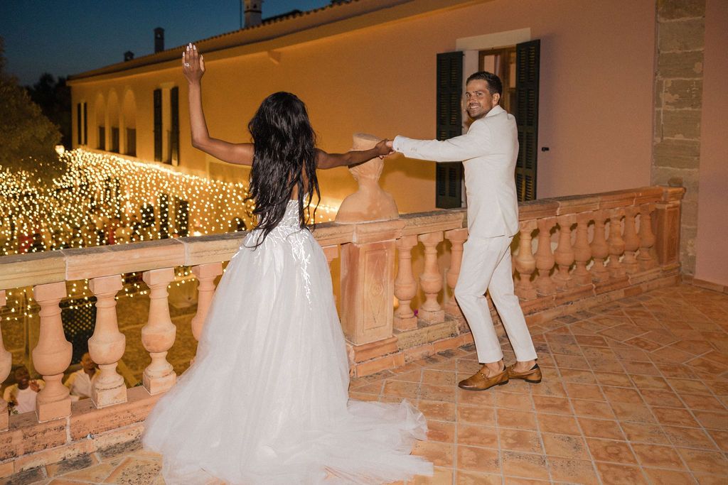 A couple dances playfully on a terrace during their wedding celebration.