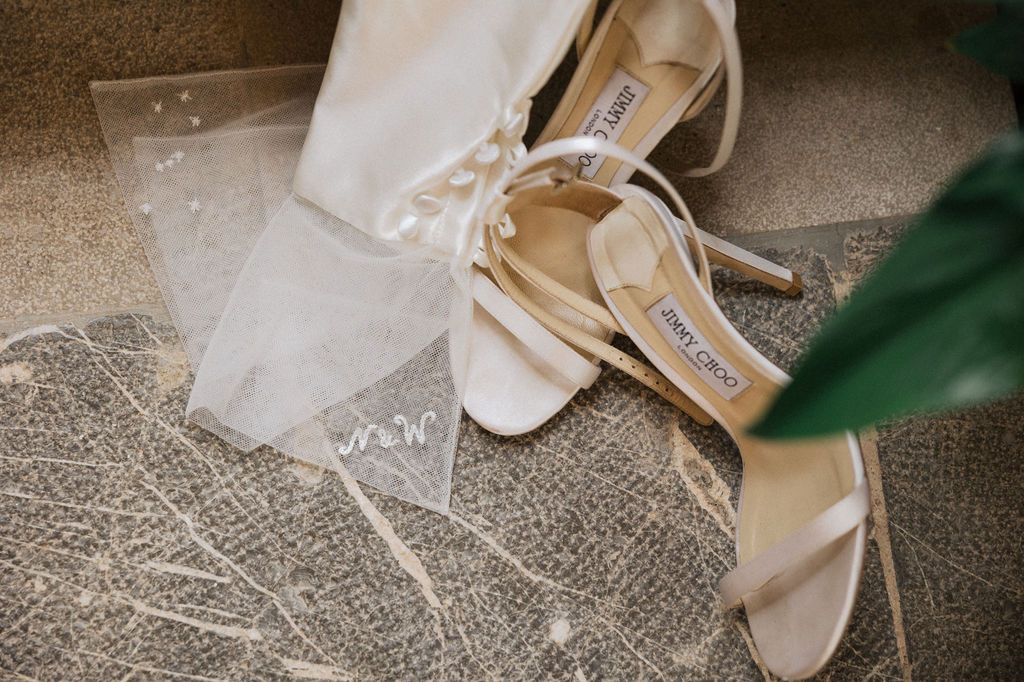 Wedding accessories including beige heels and delicate lace details on textured surface.