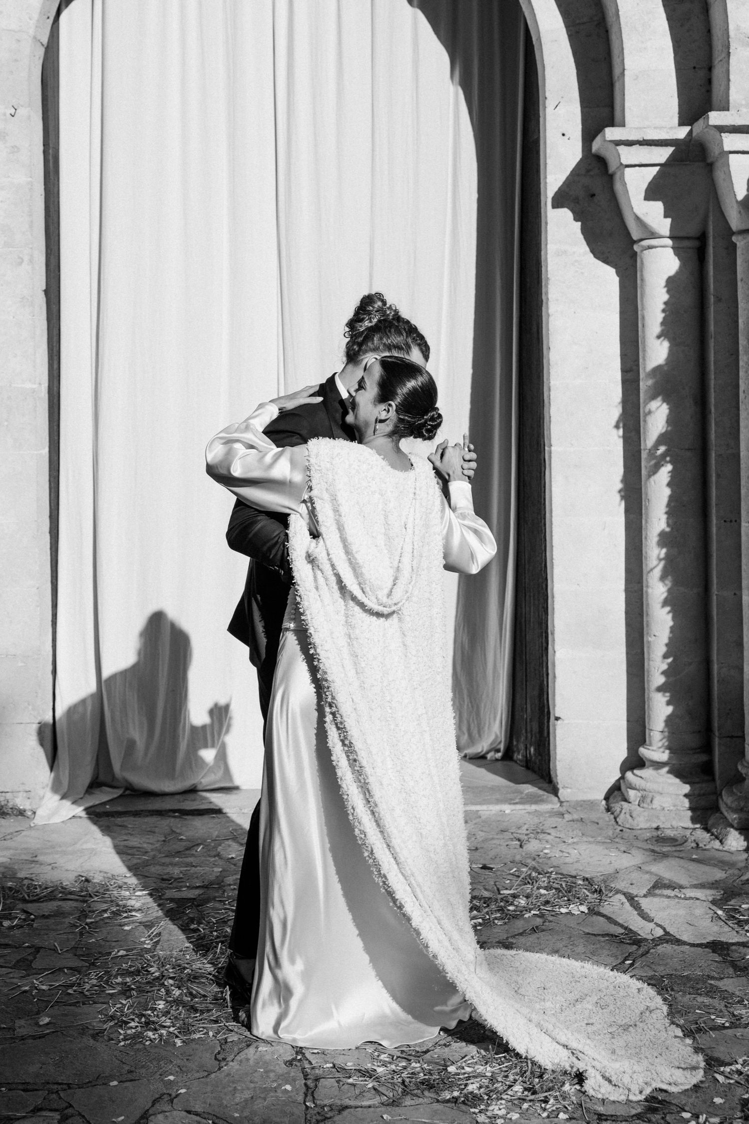 Artistic black and white sequence showing movement of bride's flowing dress against stone archways.