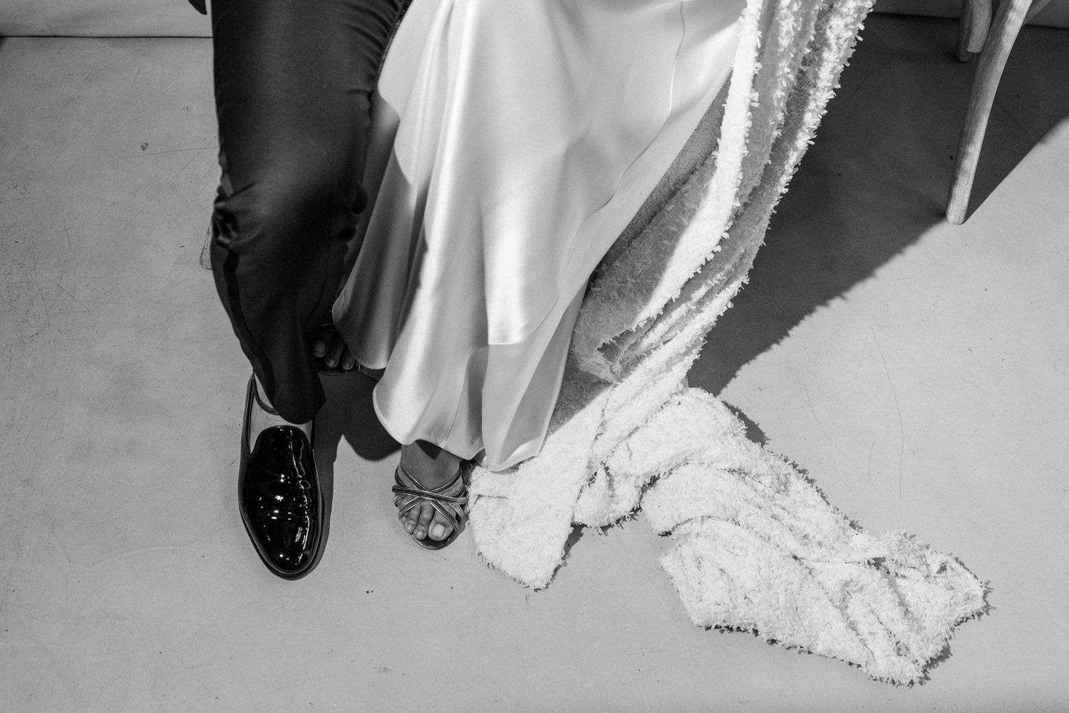 Detail shots of elegant white wedding dress and shoes against light background.