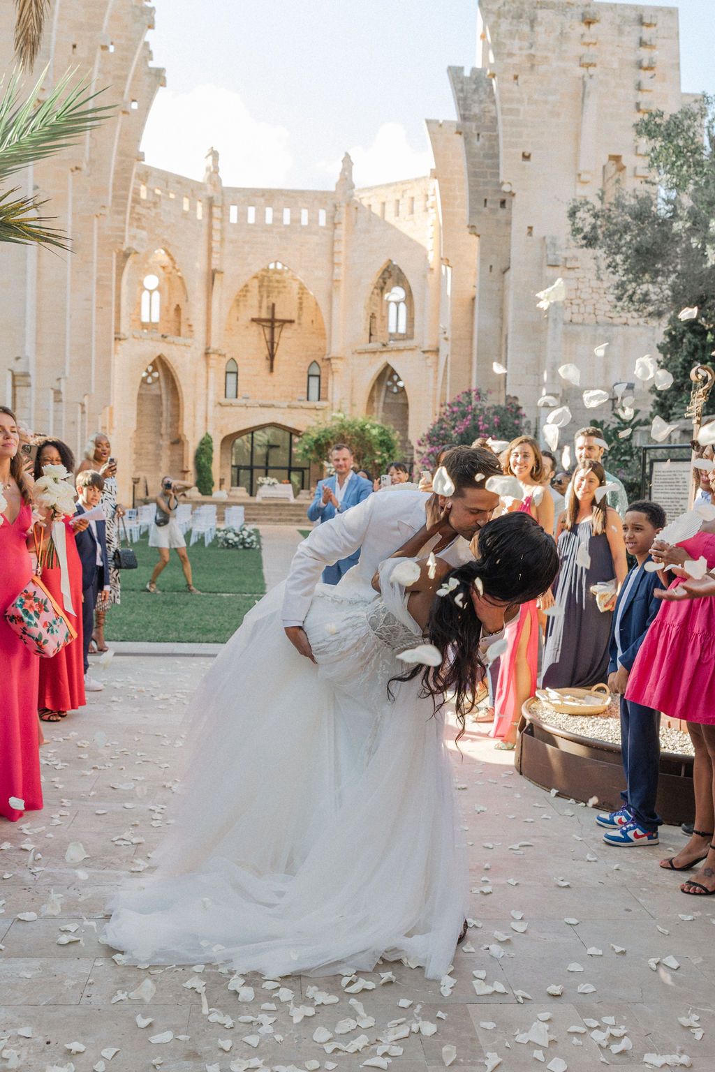 Wedding celebration at historic stone church with guests throwing flower petals.