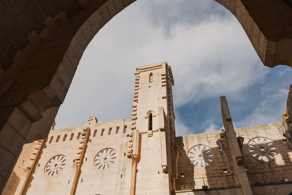 Historic stone architecture with ornate clock details viewed through arched passageways.