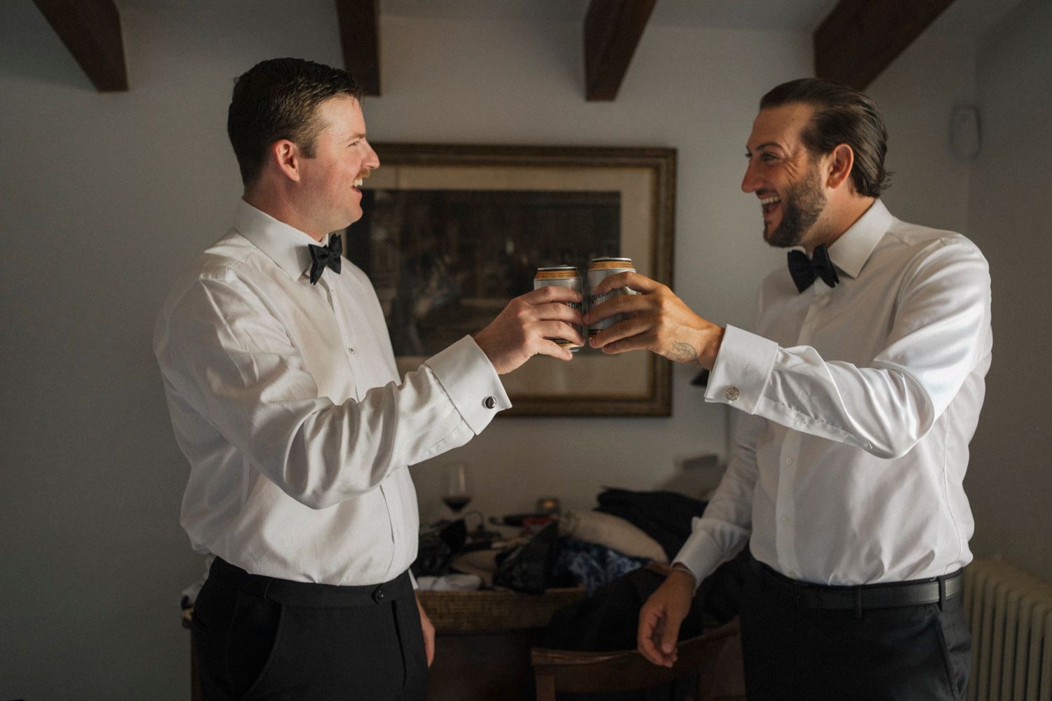Candid getting ready moments between people in white shirts in a dimly lit room.