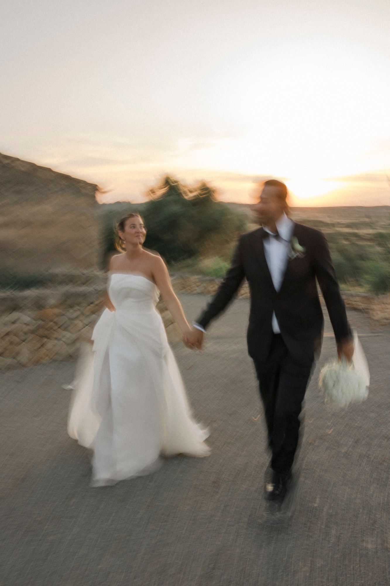 Blurred motion shots of couple dancing and twirling in wedding attire at sunset.