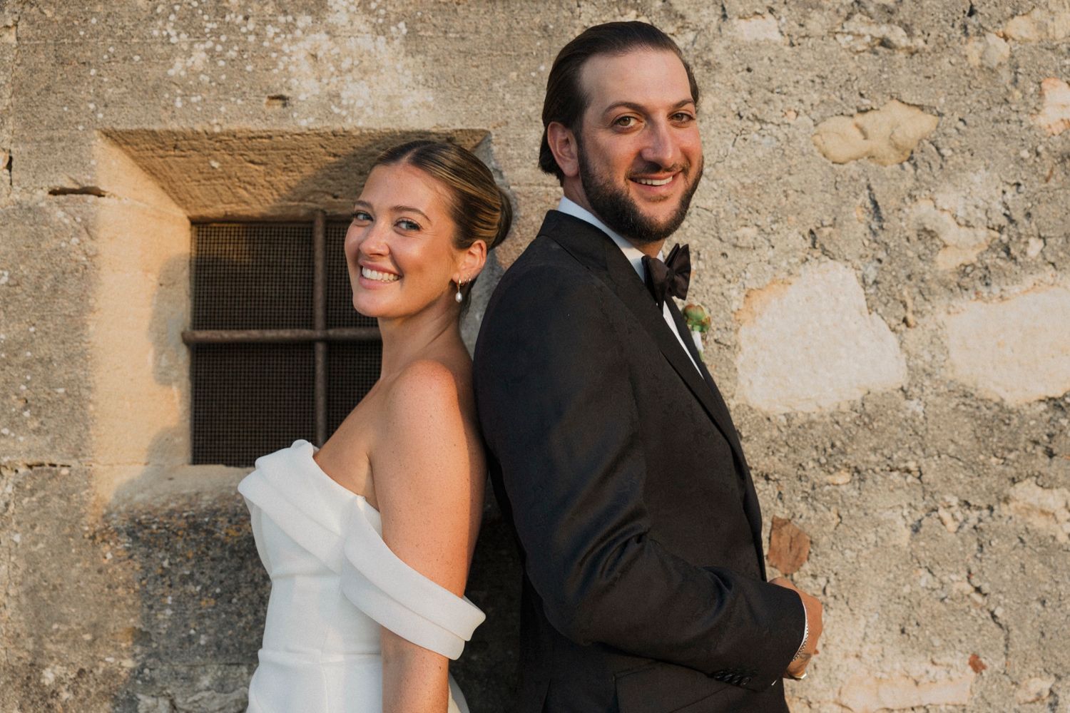 Candid wedding photos show couple sharing joyful moments against stone wall backdrop.