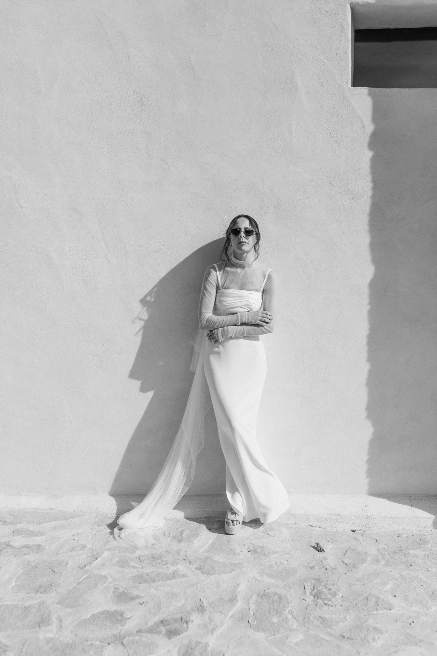 A series of four black and white photos showing a person in white clothing posing against a light colored wall.