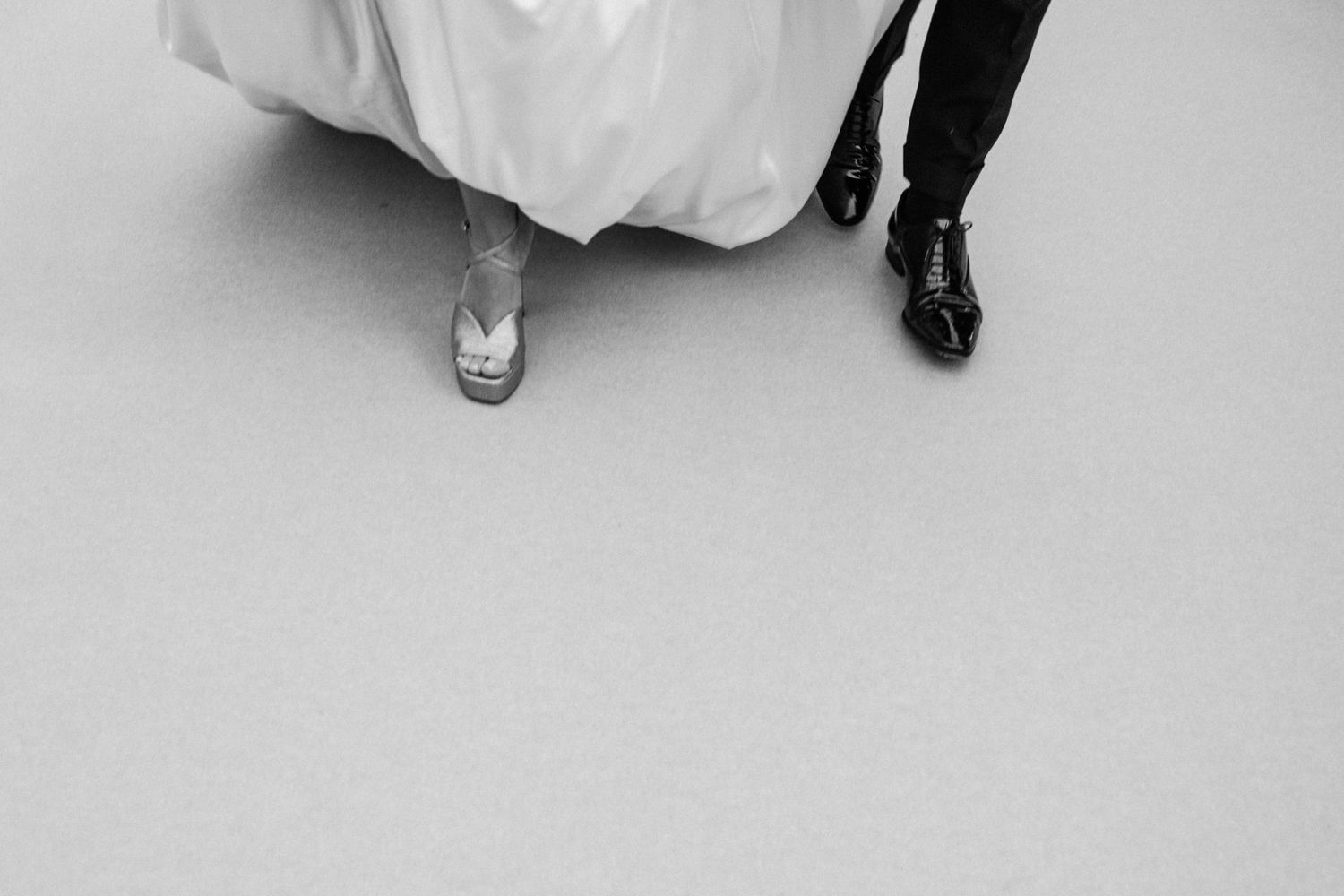 A black and white photo showing feet and legs of a couple dancing together in formal attire.