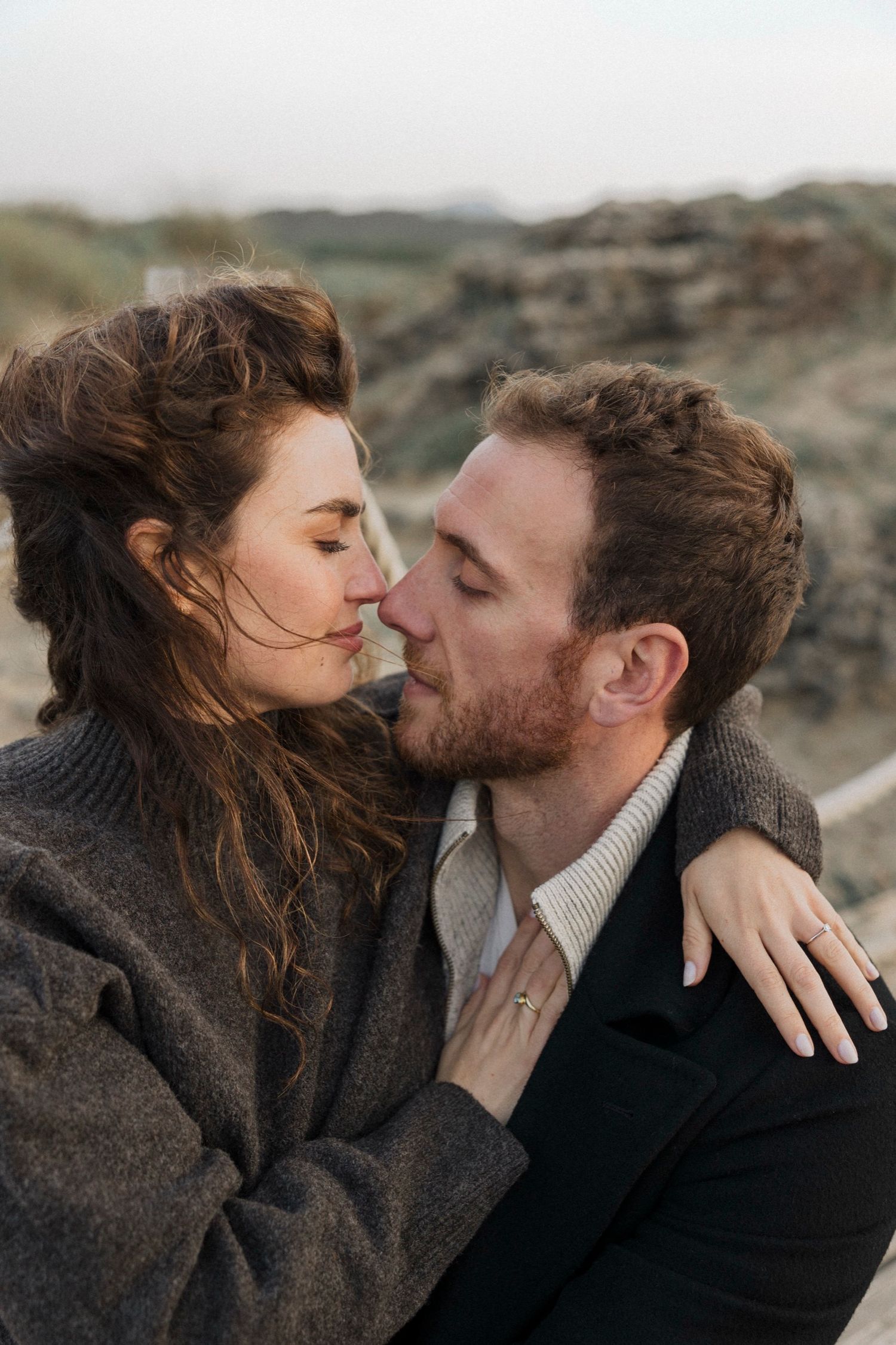 An intimate series of close-up moments between a couple in dark winter clothing against a natural backdrop.