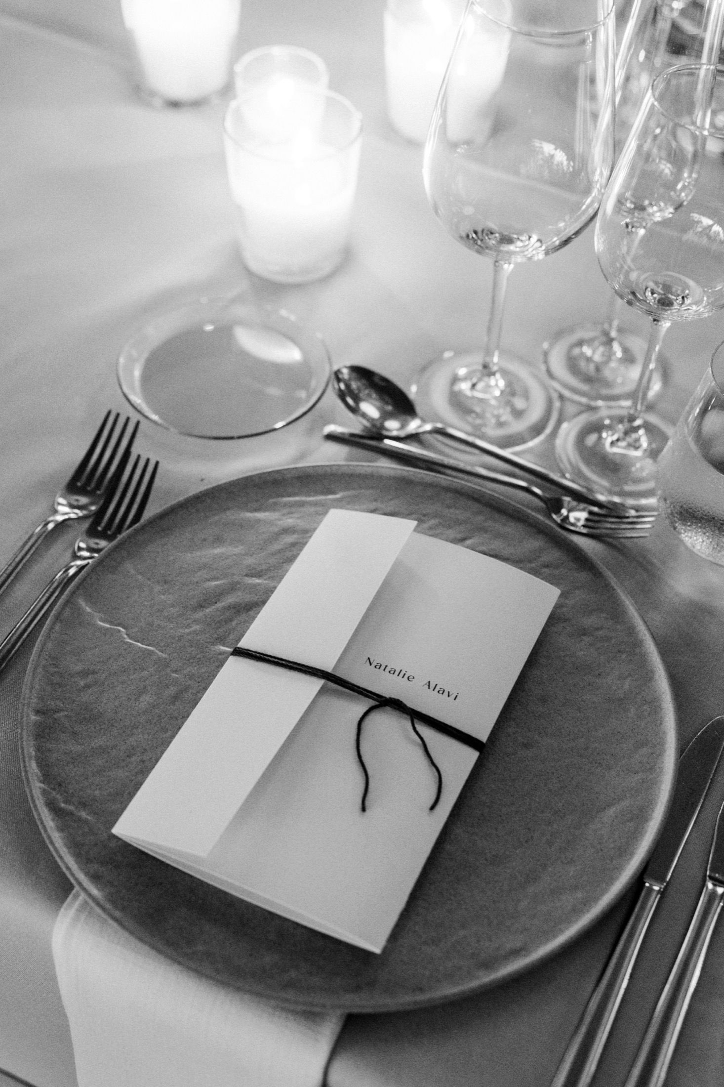 Elegant wedding place setting with menu card and wine glasses on formal dining table.