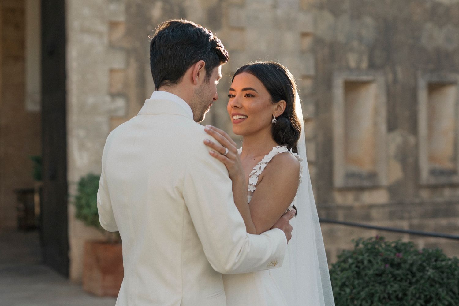 Bride and groom share a romantic embrace outdoors in golden hour light at their wedding.