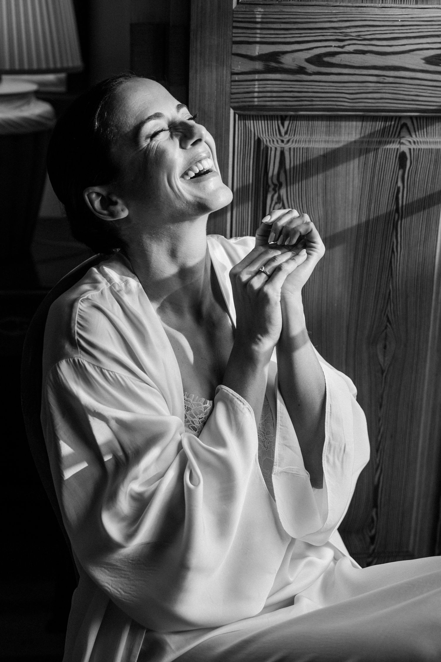 Black and white portrait captures joyful candid moment against wooden paneled walls.