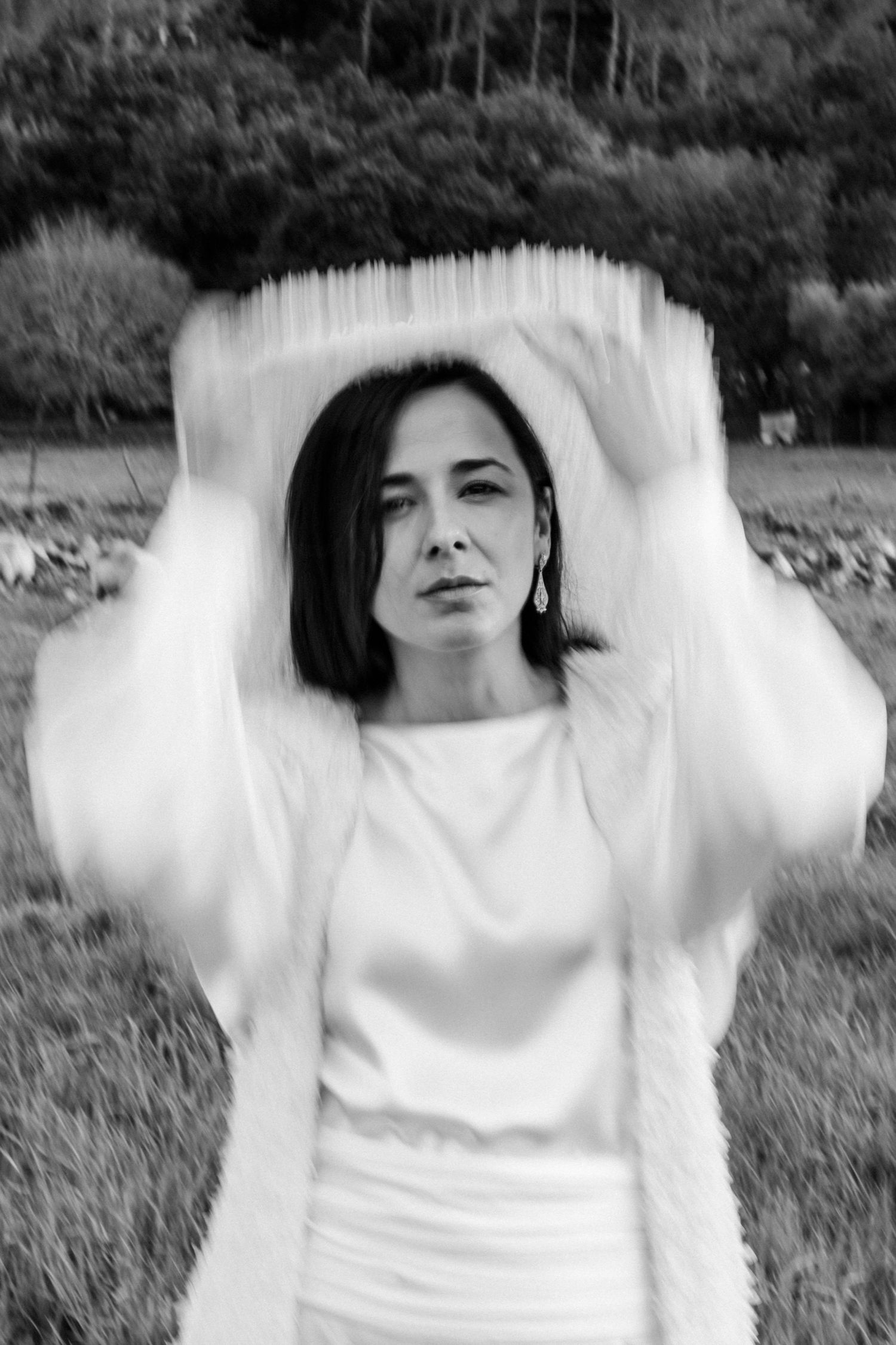 Artistic black and white sequence of a person in white spinning in a meadow.