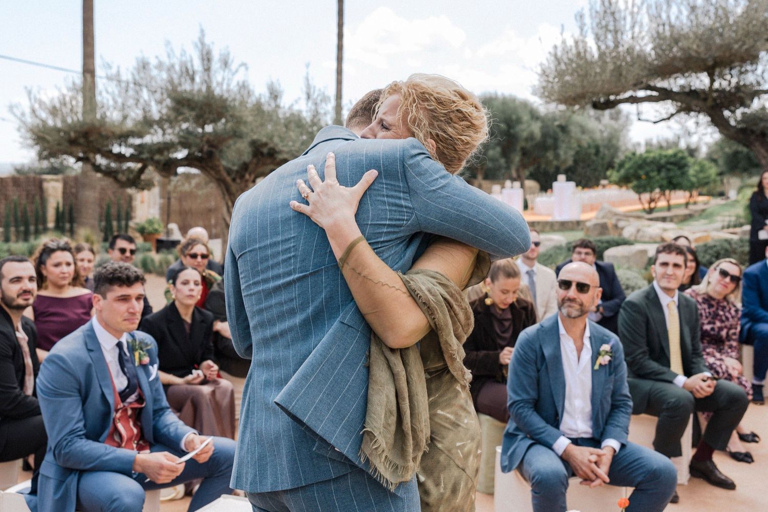 Wedding guests watch emotional first dance between newlyweds on outdoor patio at sunset celebration.