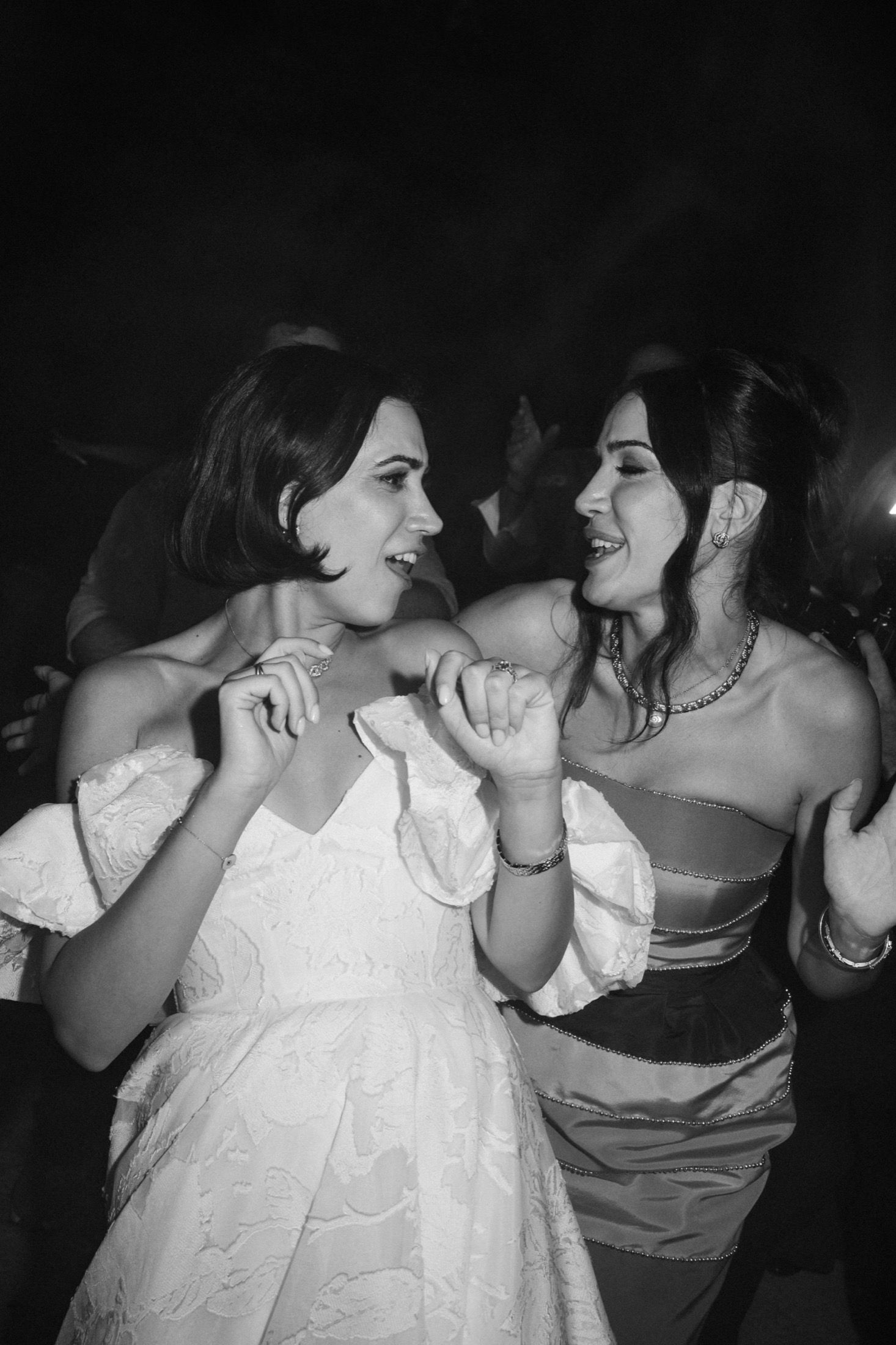 People dancing and embracing at a celebration event in black and white photography.