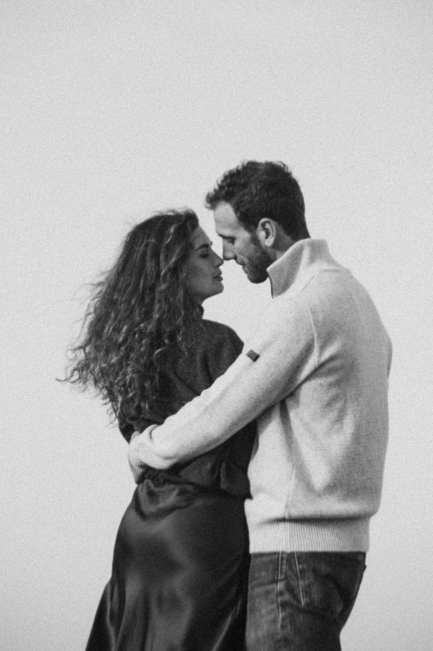 Black and white photo series showing a couple in an intimate embrace against a plain background.