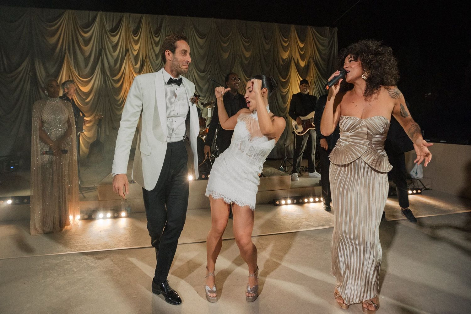 Couples dancing together at an elegant wedding reception with draped fabric decor and mood lighting.