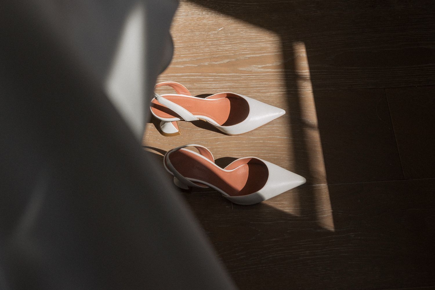 Leather shoes and boots arranged in a row on a wooden surface casting dramatic shadows.