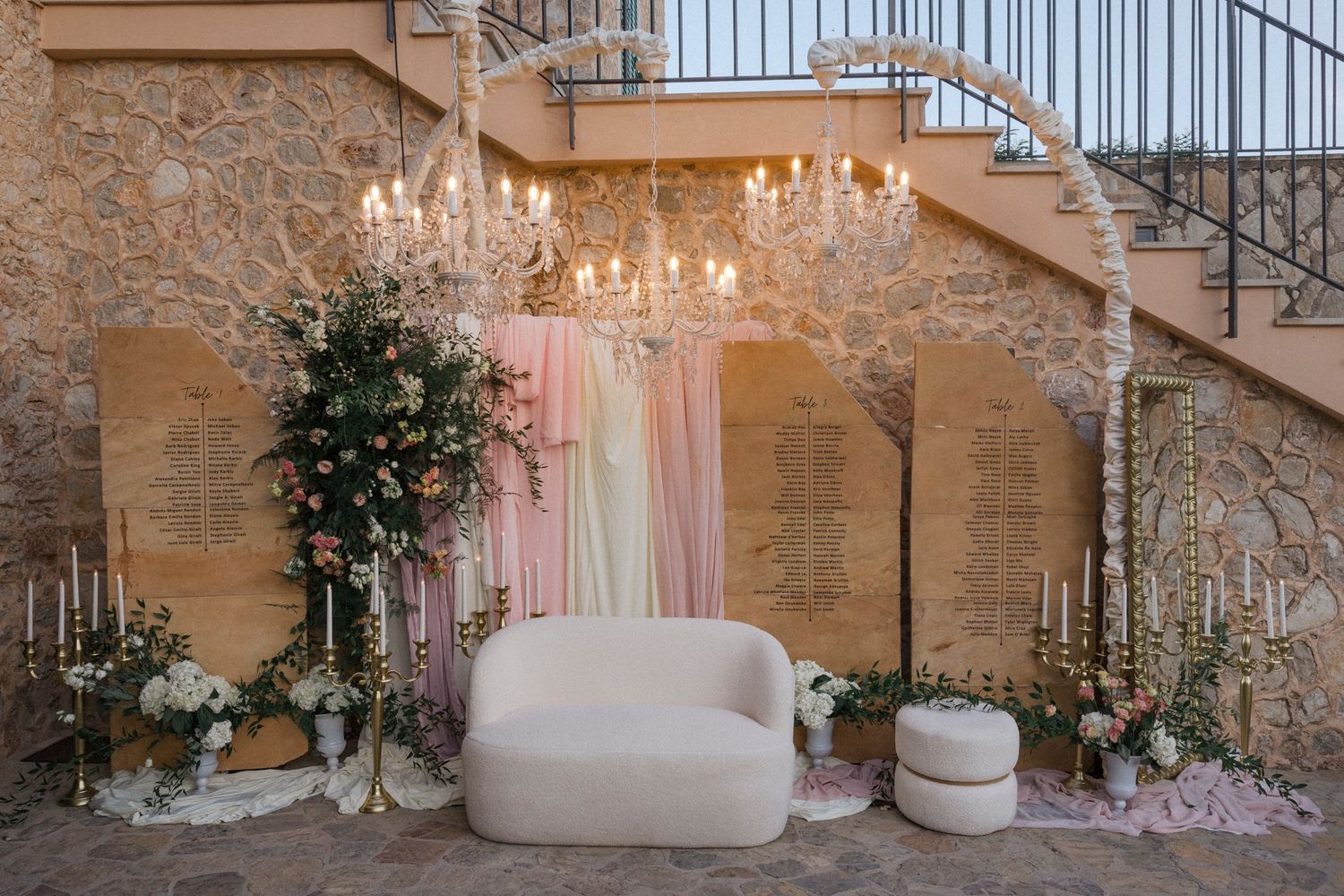 Elegant stone wedding venue interior with crystal chandeliers, white drapes, and romantic lighting creating an ethereal ambiance.