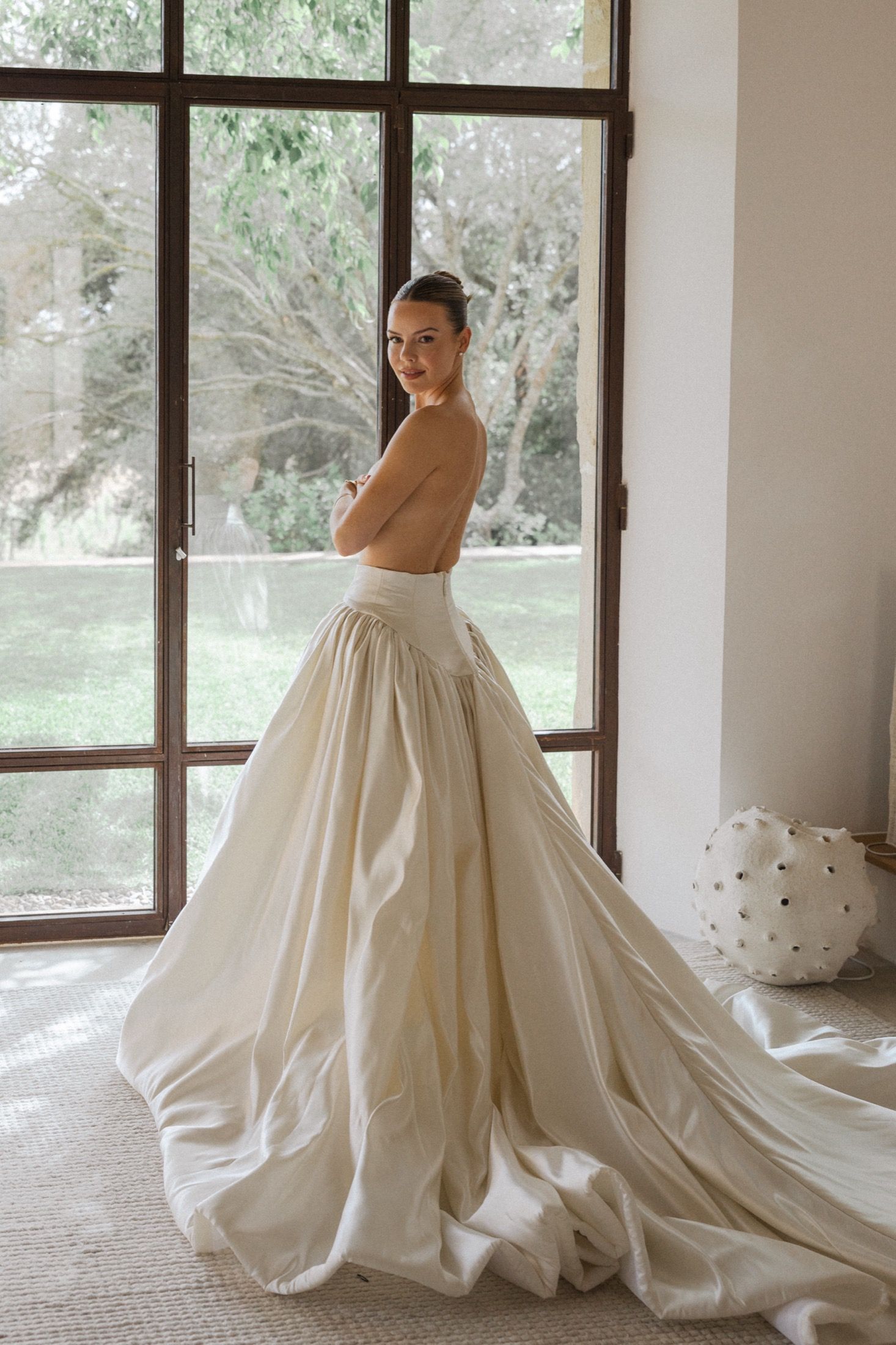 Natural light portraits of a strapless ballgown wedding dress in front of window panels.