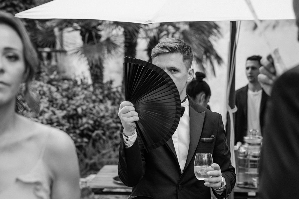 Guests enjoying drinks under a white outdoor canopy at an evening event.