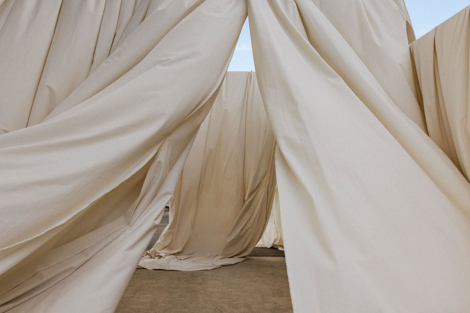Minimalist close-up of cream colored fabric draping with soft folds and texture.