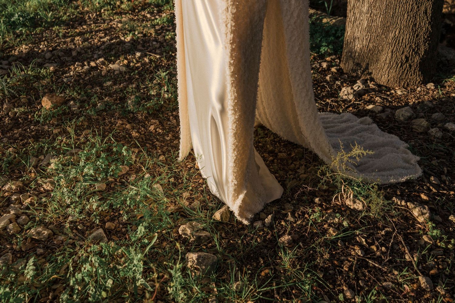 Delicate white lace dress detail photographed against autumn foliage.