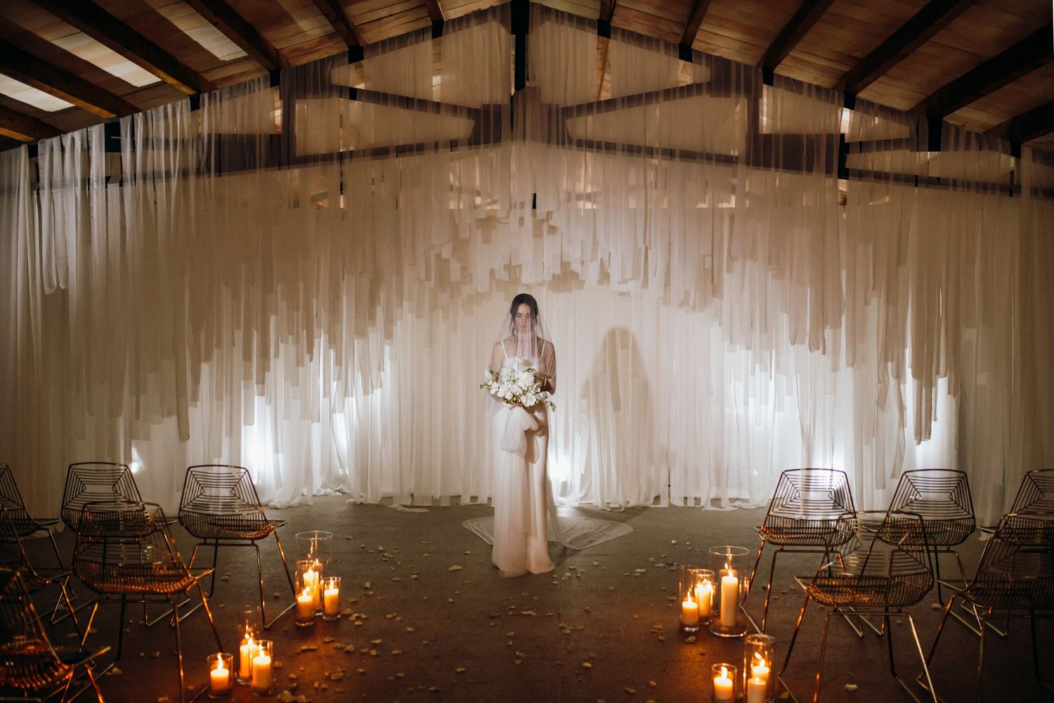 A dimly lit wedding reception venue with candles and empty chairs creating a romantic atmosphere.