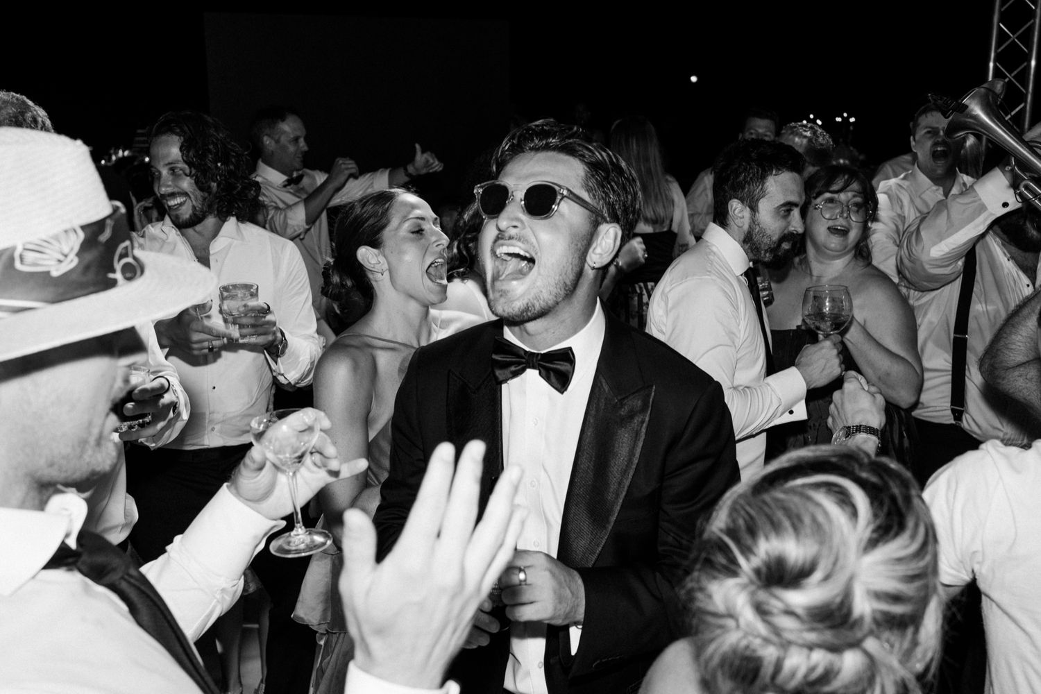 Wedding guests celebrate with joyful expressions during a lively reception party.