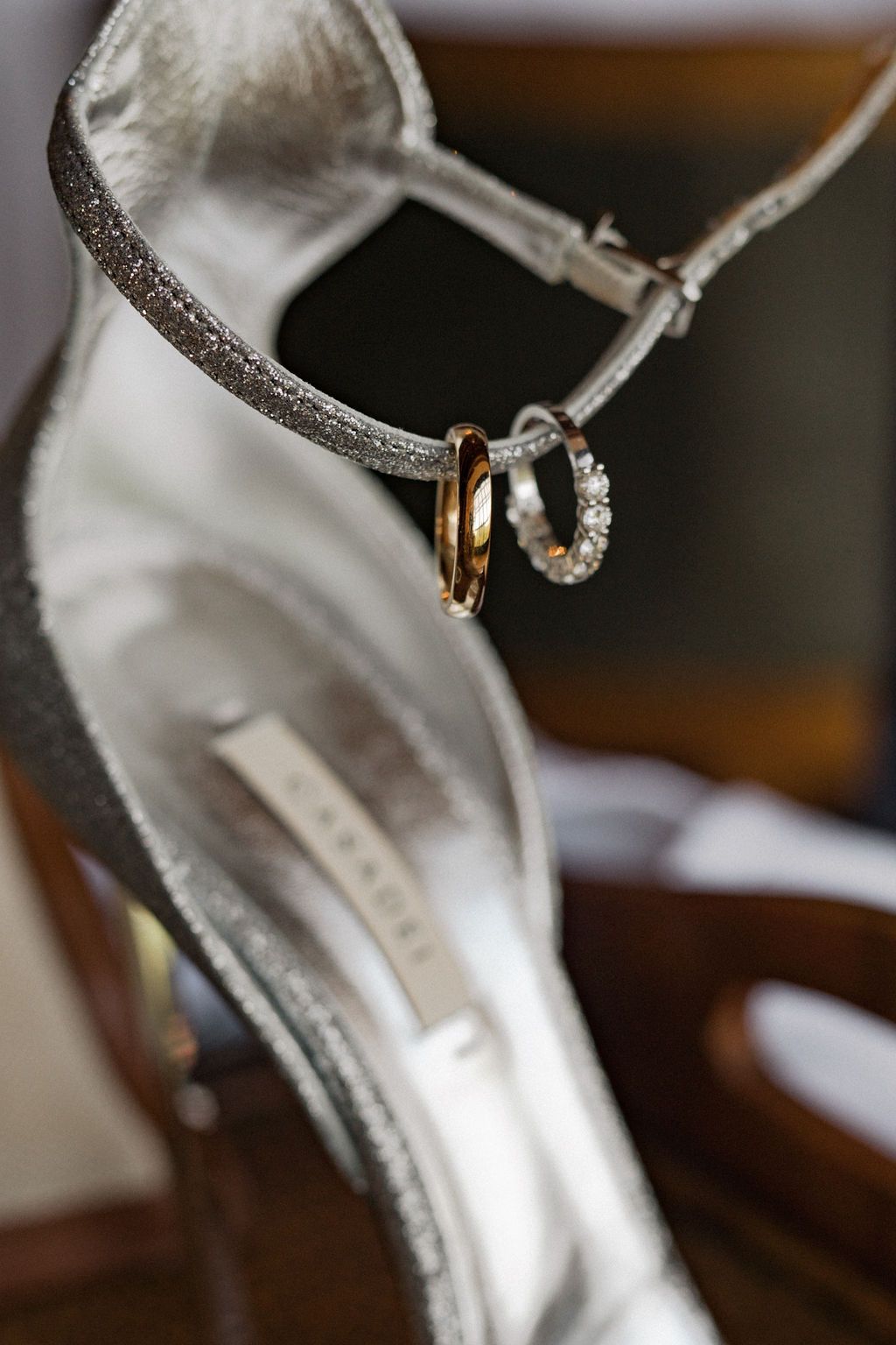 Close-up detail of silver and gold wedding rings on sparkly shoe strap.