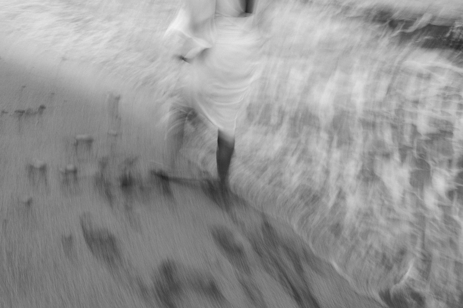 Abstract motion blur photograph of person in white against textured background.