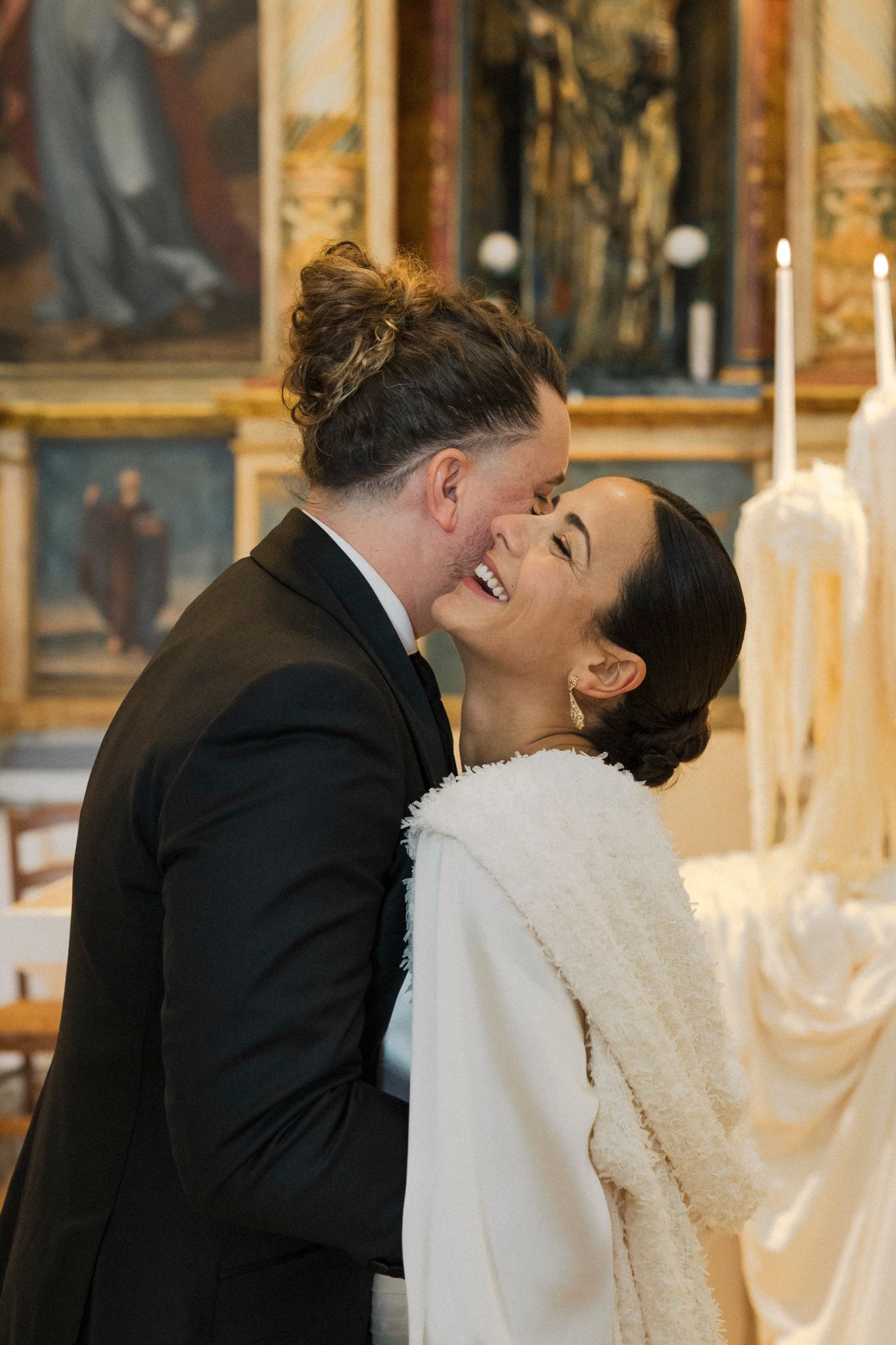 Joyful wedding moment shared between couple surrounded by ornate church architecture.